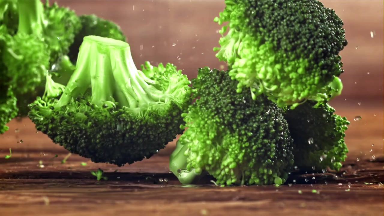 Green Broccoli Florets Falling and Splashing Water on Wooden Surface