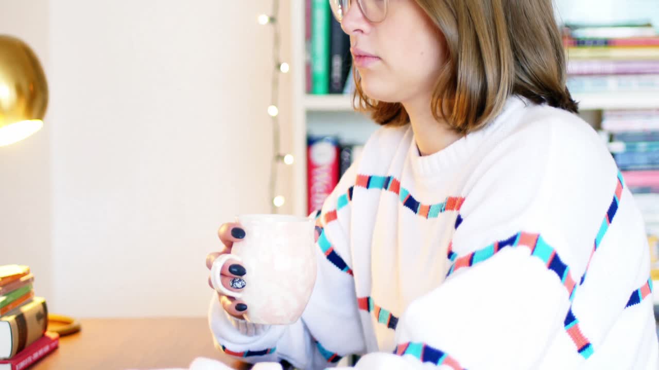 mujer usando una computadora portátil mientras toma una taza de café