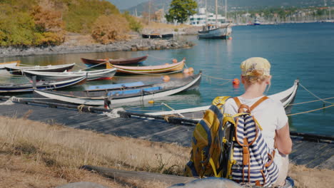 una mujer con una mochila se sienta en el paseo marítimo de la ciudad de oslo en noruega cerca de los barcos de pesca