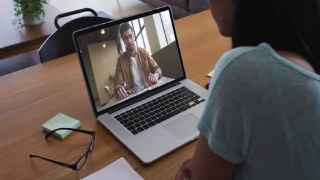 mid section of african american woman having a video call with male colleague on laptop