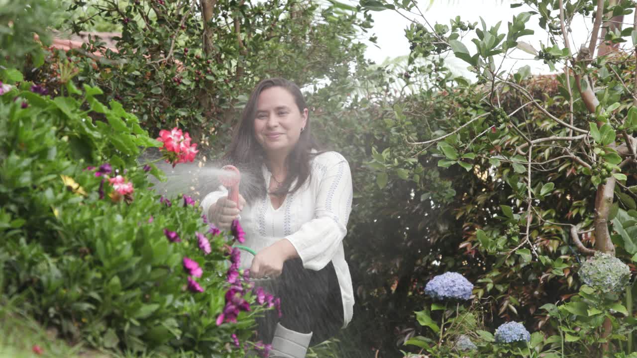 mujer regando flores. actividades de jardinería detrás de la casa