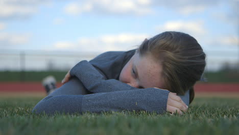 Eine-Sportlerin-Legt-Sich-In-Das-Gras-Eines-High-School-Fußballfeldes