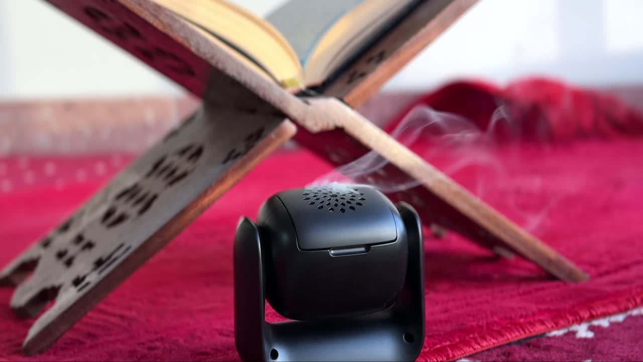 4K close-up of incense smoke rising in front of an open Quran on a wooden rehal. Captures a serene, spiritual atmosphere. Ideal for Ramadan, prayer, or Islamic-themed content.