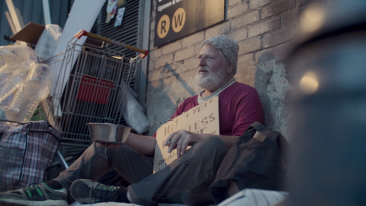Elderly Homeless Man Holding Sign, Smoking and Begging for Money on Sidewalk