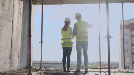 Bauarbeiter,-Die-Auf-Einer-Baustelle-Arbeiten.-Bauarbeiter-Schauen-In-Den-Kopierraum-Der-Rückansicht-Des-Bauplans.-Teamarbeit-Und-Personalkonzept-Für-Die-Gebäudeentwicklung.