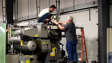 two men taking a electric motor off a dry cleaning machine