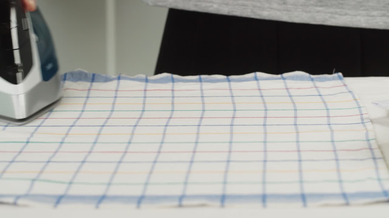 Close-up of a Hand Ironing a Checkered Cloth