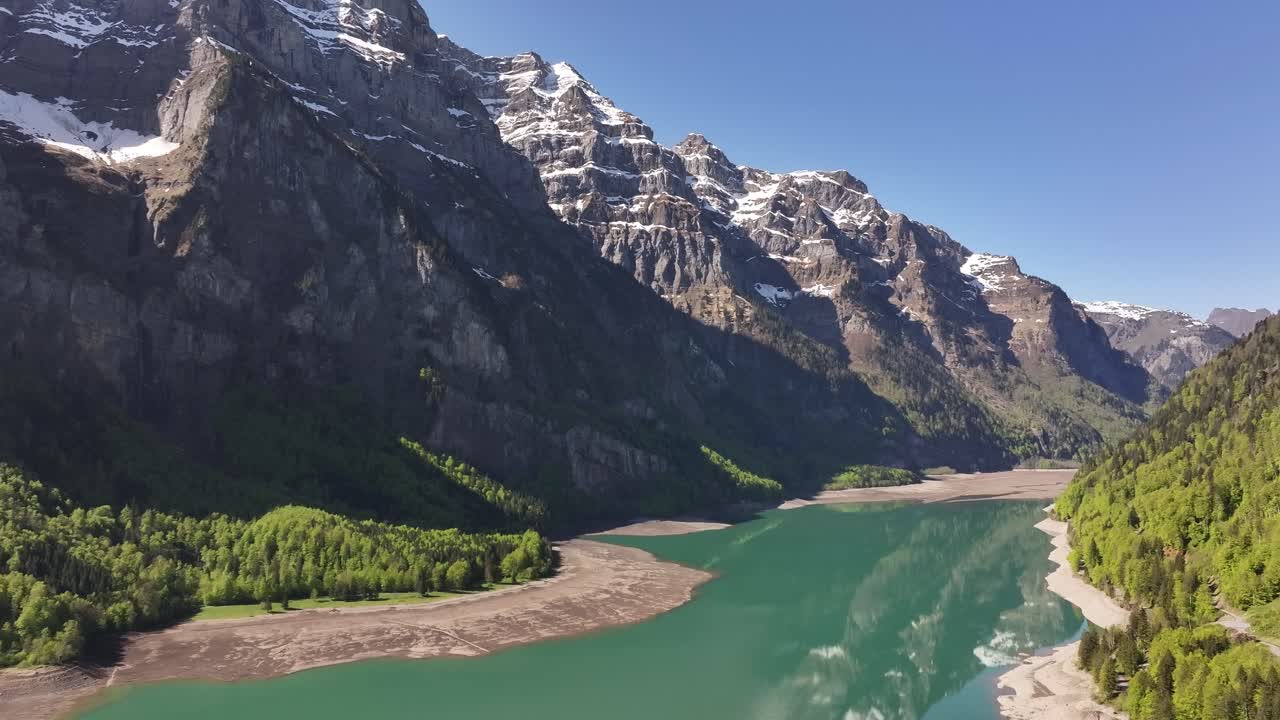 turquoise Klöntalersee lake surrounded by alpine peaks and forests in Glarus Switzerland - Aerial