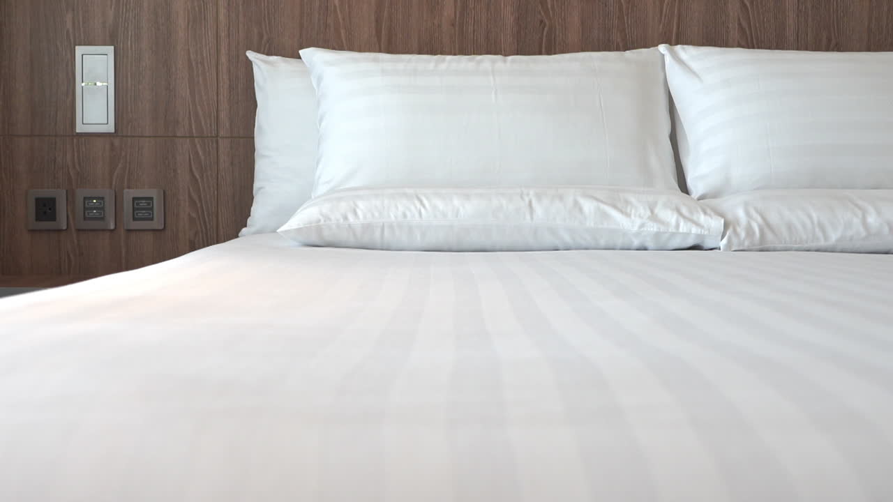 Right pan shot of a very clean and comfortable hotel room bed