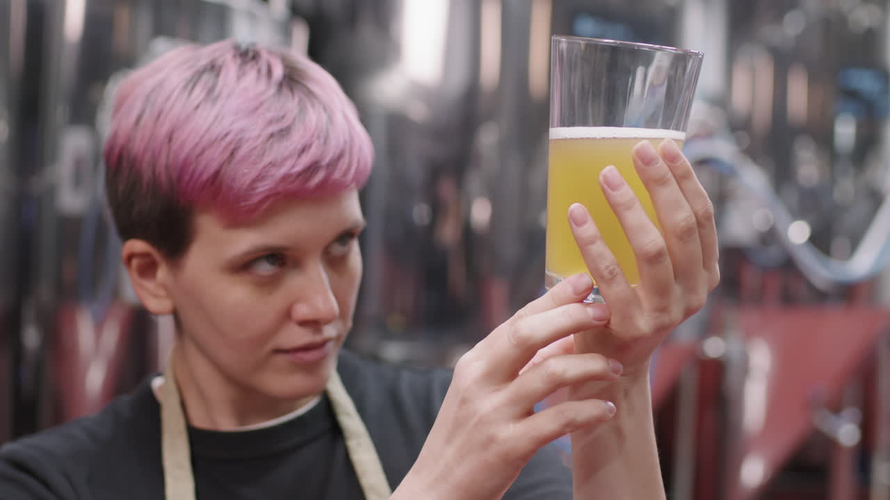 Female Brewery Worker Inspecting Freshly Made Beer