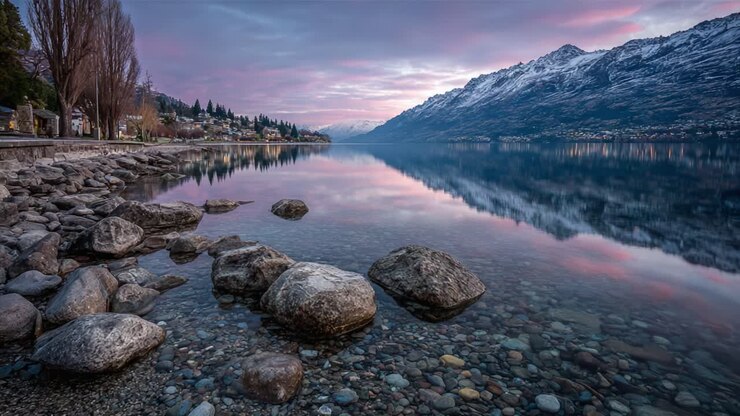 Una serata serena al lago: riflessi incantevoli e acque tranquille tra maestose montagne sotto un cielo crepuscolare.