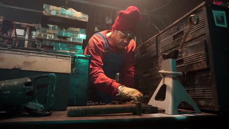 workman arranges tools on workbench and walks out of shot