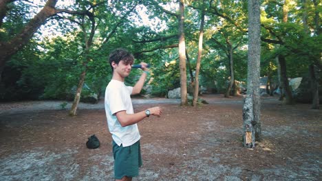 young teenage man throwing axe into tree trunk in forest in fontainebleau sport