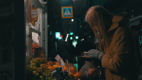 mujer comprando fruta en un puesto callejero