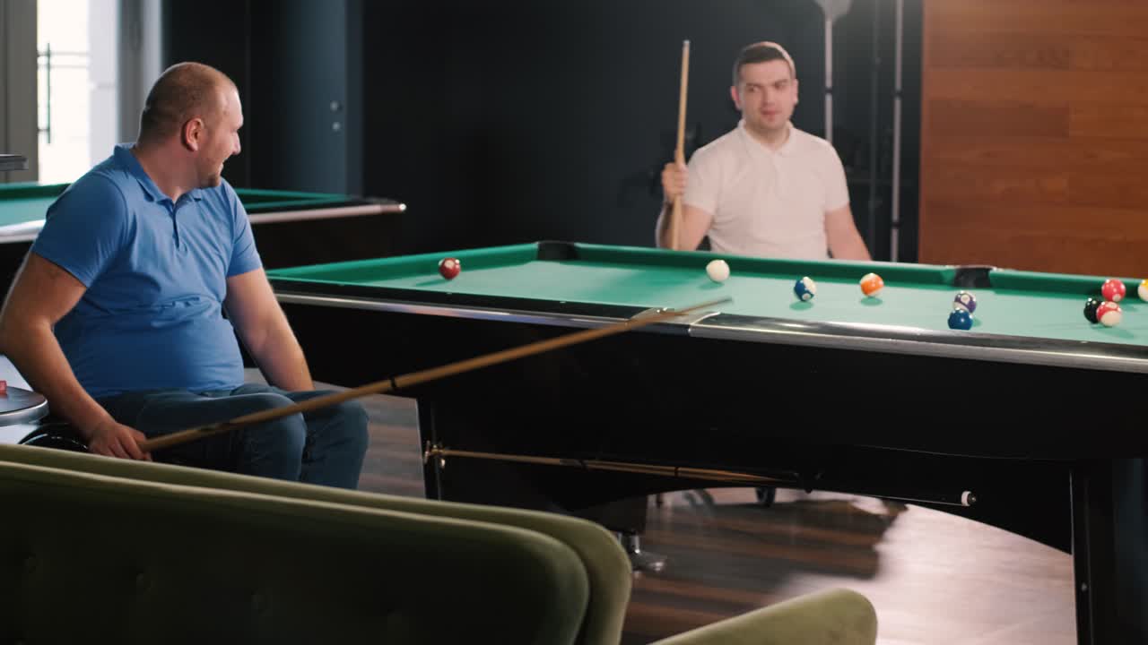 Adult men with disabilities in a wheelchair play billiards in the club