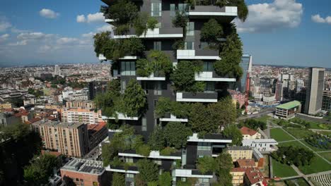 drone captures a city-center building adorned with vertical forest greenery, surrounded by high-rise and low-rise structures, blending nature with urban architecture in striking detail.