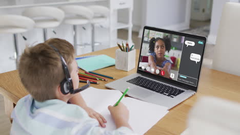 schoolboy using laptop for online lesson at home, with school friend and web chat on screen
