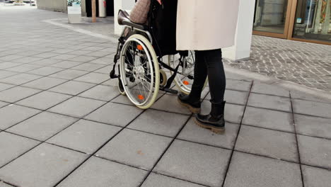 woman pushing a wheelchair on the sidewalk