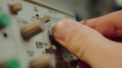 Closeup-of-finger-operating-a-switch,-a-knob-and-manipulating-a-highly-sophisticated-electronic-vintage-device