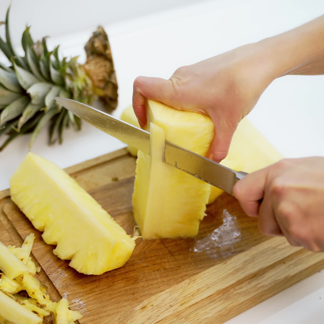 Woman cutting pineapple. Fresh pineapple on the cutting board. Hands of a female preparing exotic fruit for guests. Close-up.