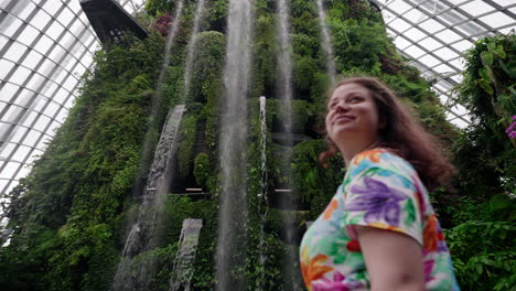 woman tourist viewing the indoor man-made waterfall of cloud forest, gardens by the bay in singapore