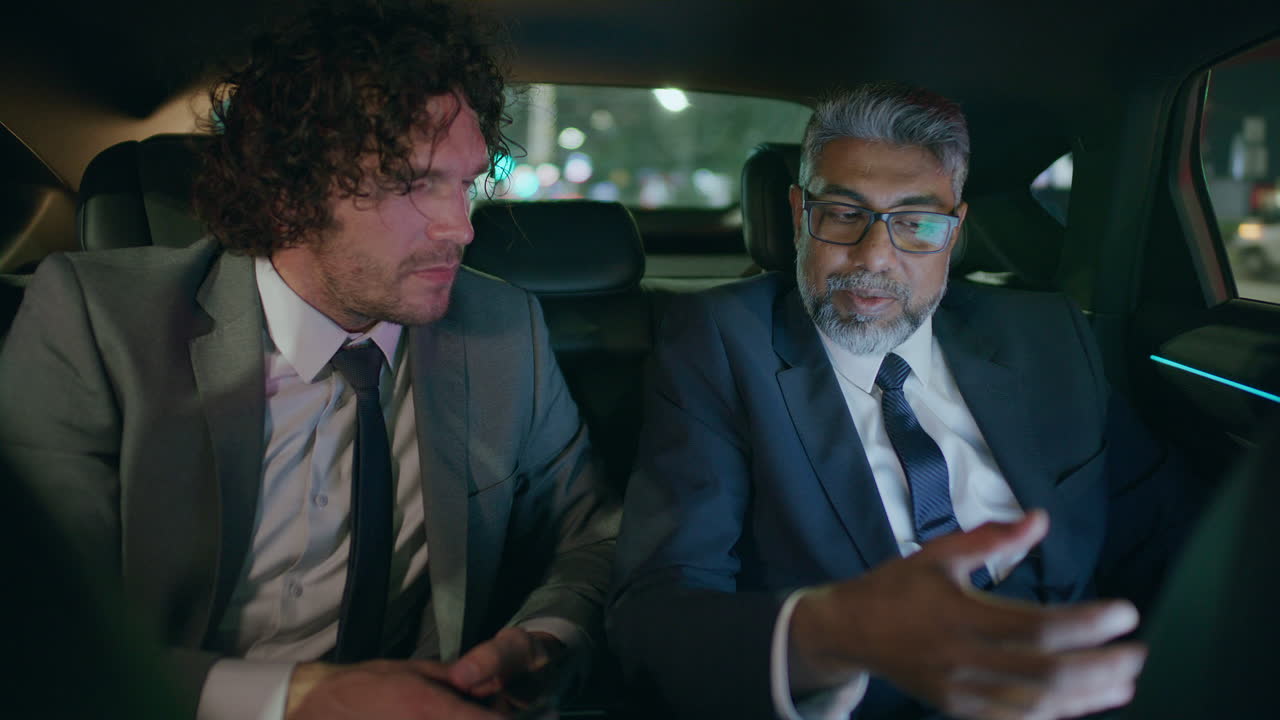 Senior Businessman Discussing Project on Laptop with Colleague in Car