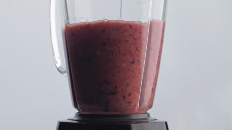 shaker eléctrico mezclando batido en súper cámara lenta de cerca. nutrición vegana.