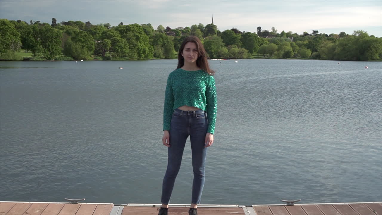 hermosa modelo de moda italiana posando con su atuendo frente a un lago en londres a la hora dorada