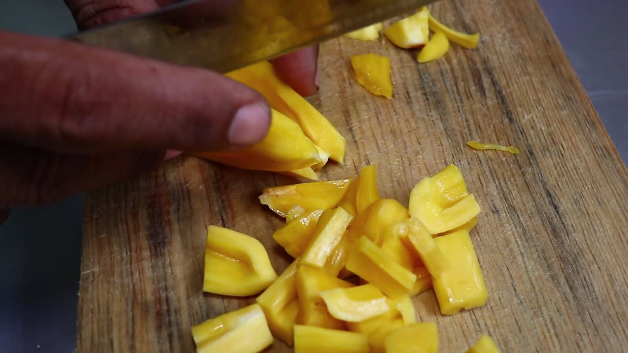 cortar jackfruit amarillo fresco con un cuchillo en una bandeja de madera