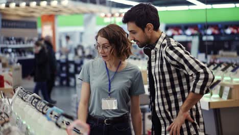 en la tienda de electrónica, una consultora da consejos profesionales a un joven que considera comprar un nuevo teléfono inteligente y