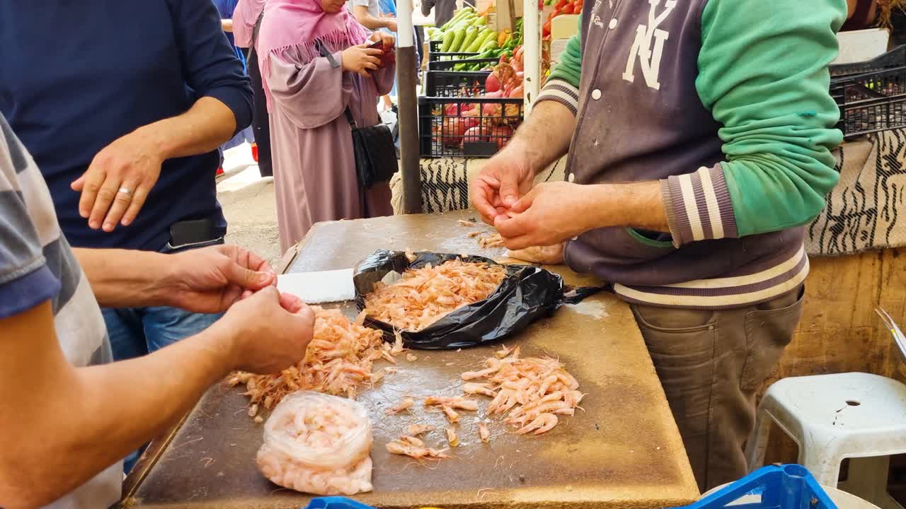 Close up of two men peeling shrimp on a sunny morning in downtown Algiers, Algeria