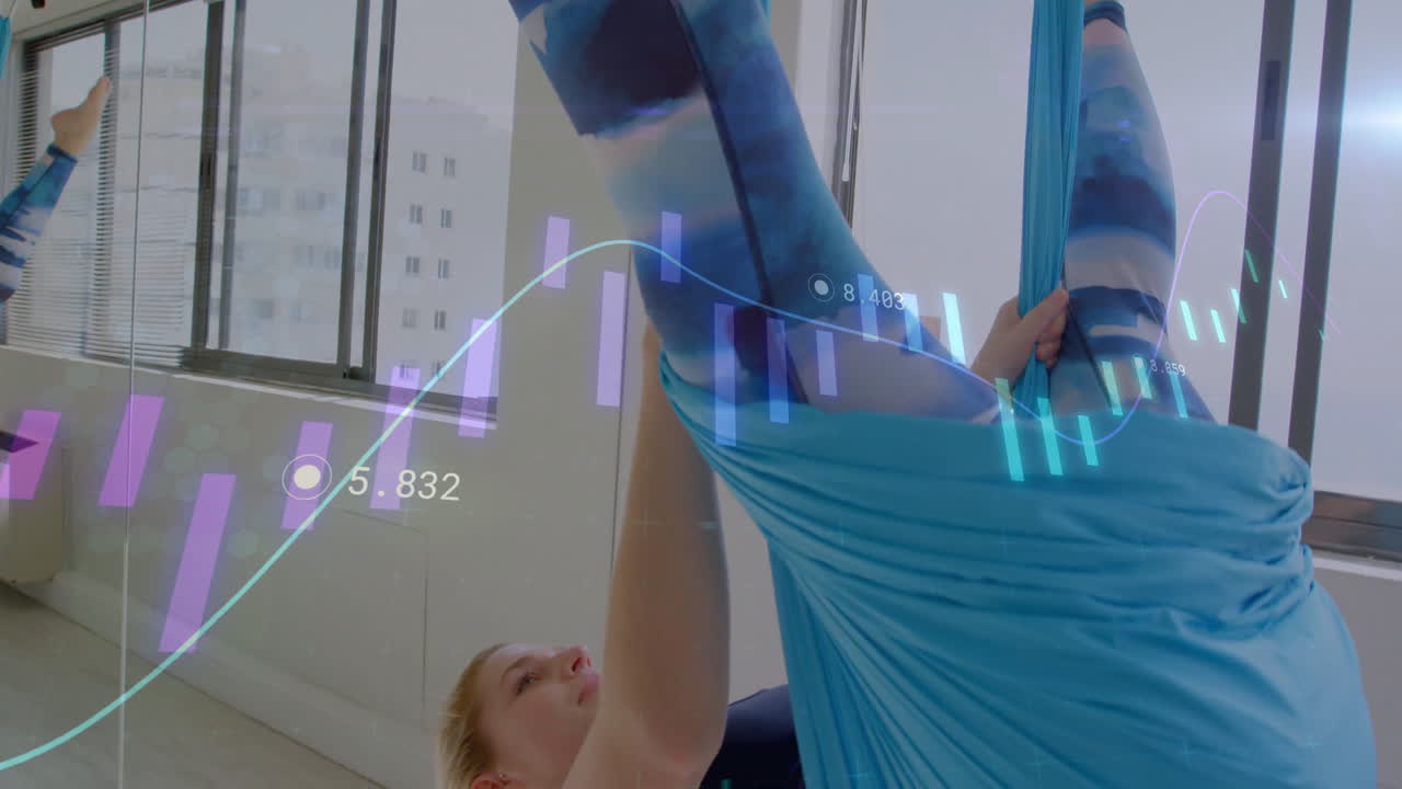 woman practicing aerial yoga inside fitness studio, displaying holographic fitness data charts