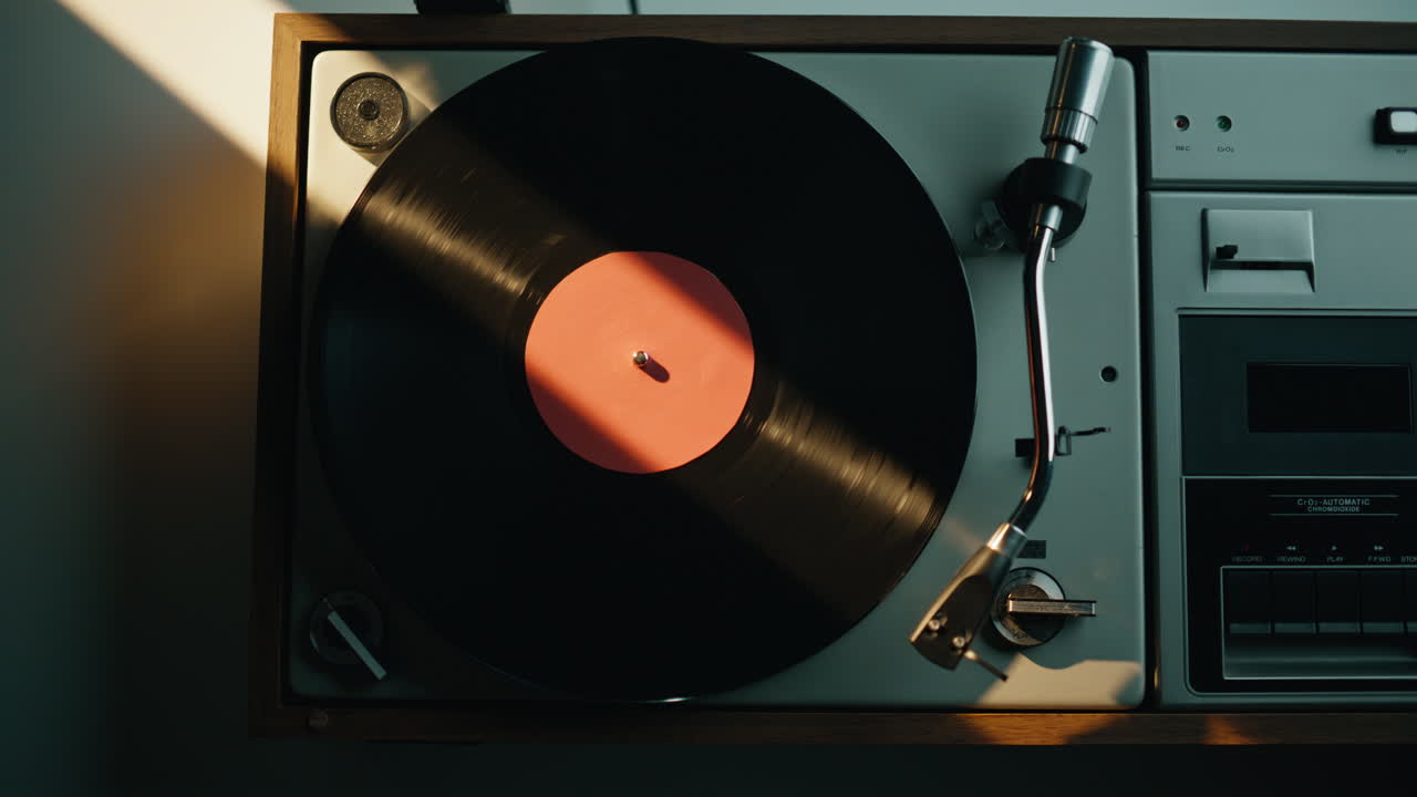 Hand turning off vinyl player in quiet apartment lit by evening light closeup