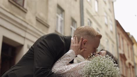 recién casados, novio caucásico con novia caminando, abrazándose, abrazándose en la ciudad, pareja de bodas enamorada