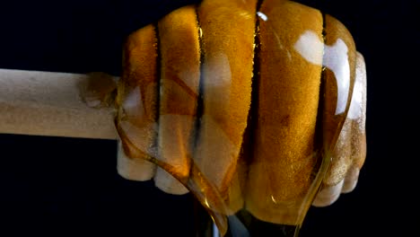pouring honey to dripper stick againt black blackground