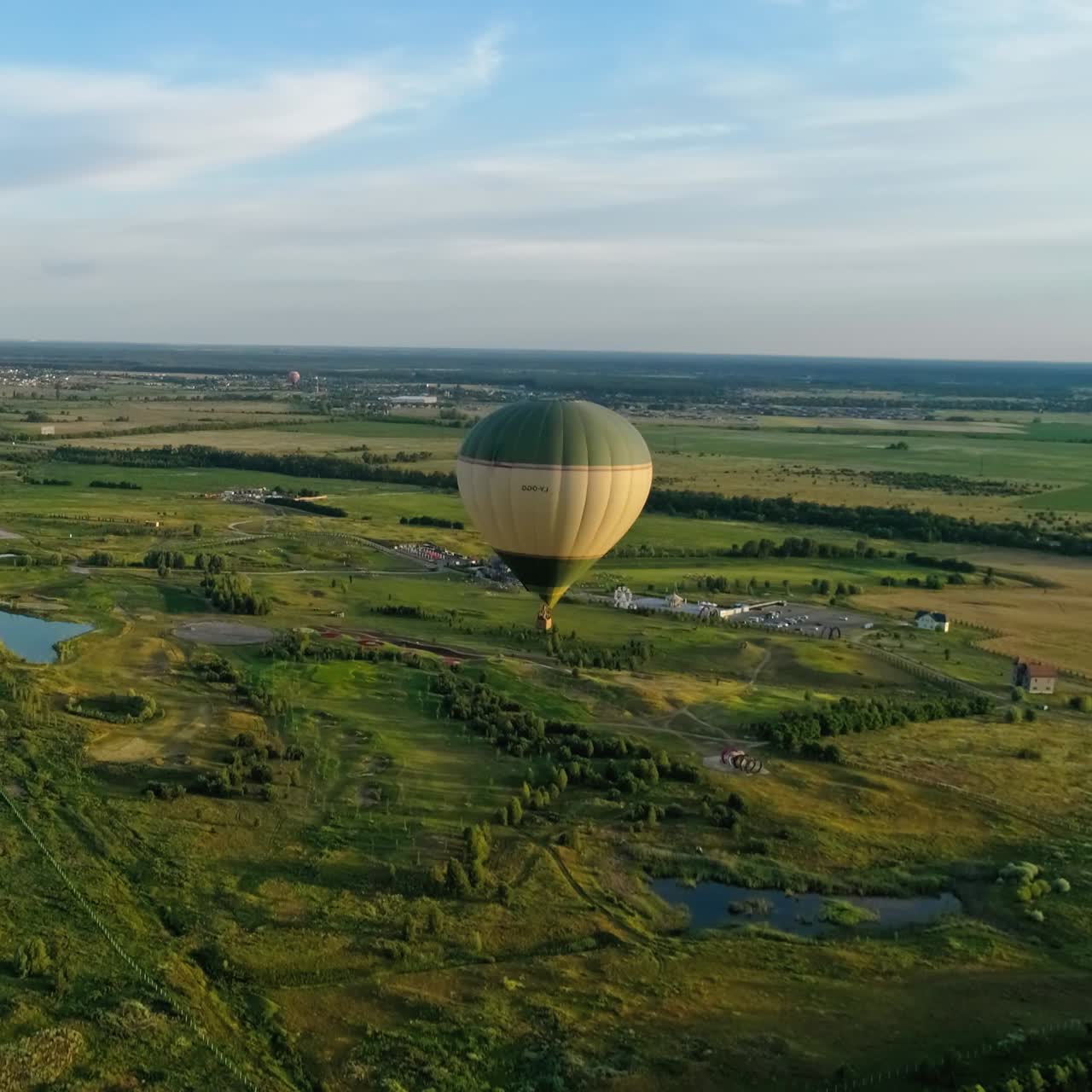 Colorful aerostats among nature. Hot air balloons fly in the sky over fields and lakes in the countryside. Aerial view.