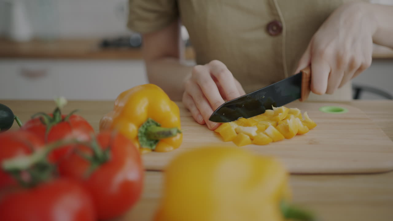 Woman chopping yellow pepper in kitchen