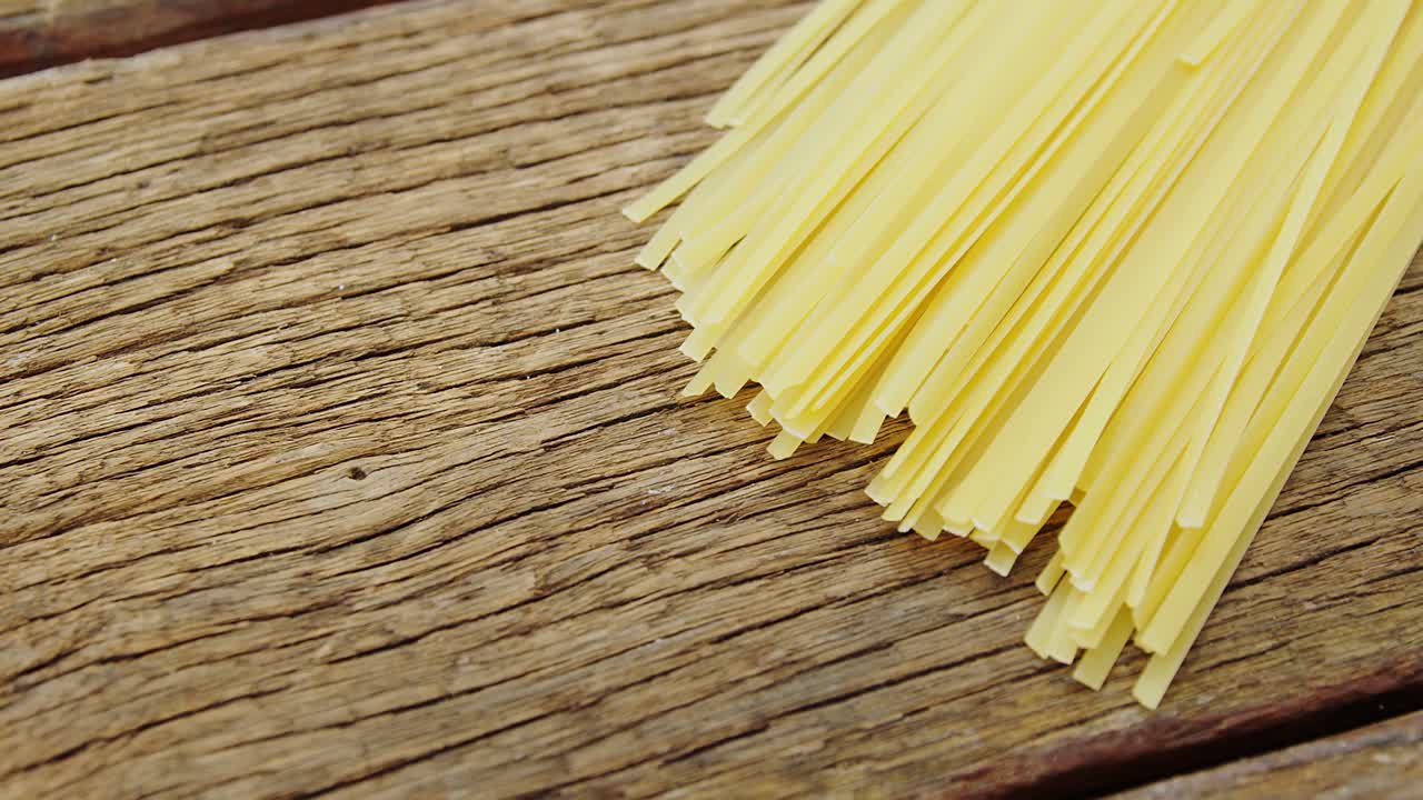 Uncooked tagliatelle pasta on wooden table background