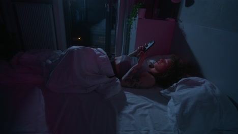 woman using phone in bed at night