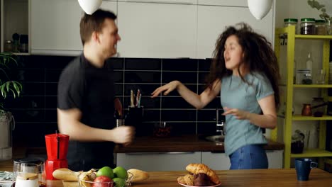 una joven pareja alegre y atractiva enamorada bailando juntos un baile funky en la cocina en casa en vacaciones