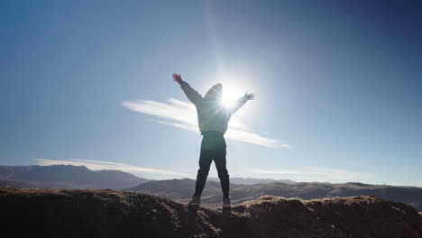 silhouette of person raising arms in triumph against sunrise over mountain ridge