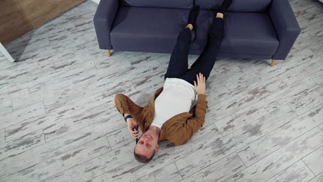 man relaxing using mobile phone. happy young man talking on mobile phone and lying on the floor