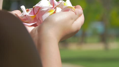 mujer soplando pétalos de flores de las manos