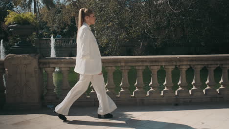 stylish young woman walking through old park.