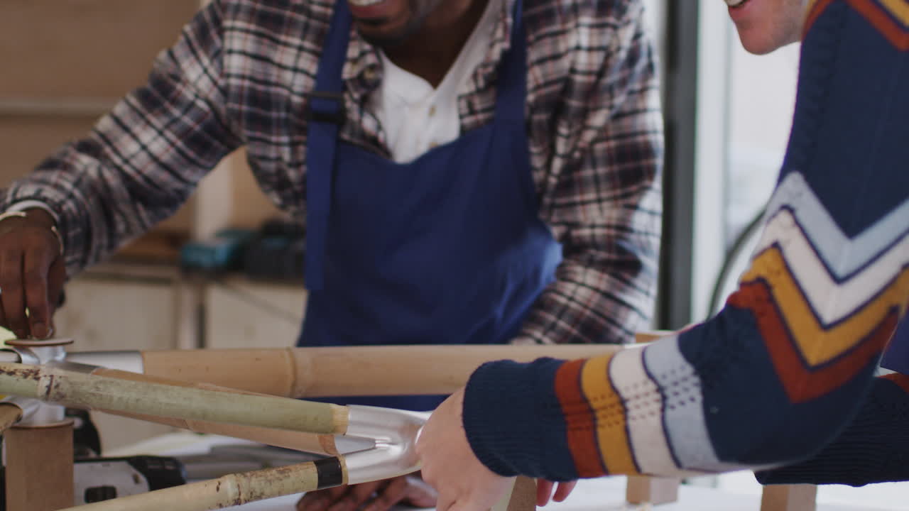 Multi-Cultural Team In Workshop Assembling Hand Built Sustainable Bamboo Bicycle Frame