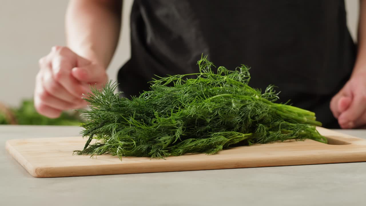 Cutting dill, chef cut dill with knife on a wooden board, close up at home, vitamin vegan greens.
