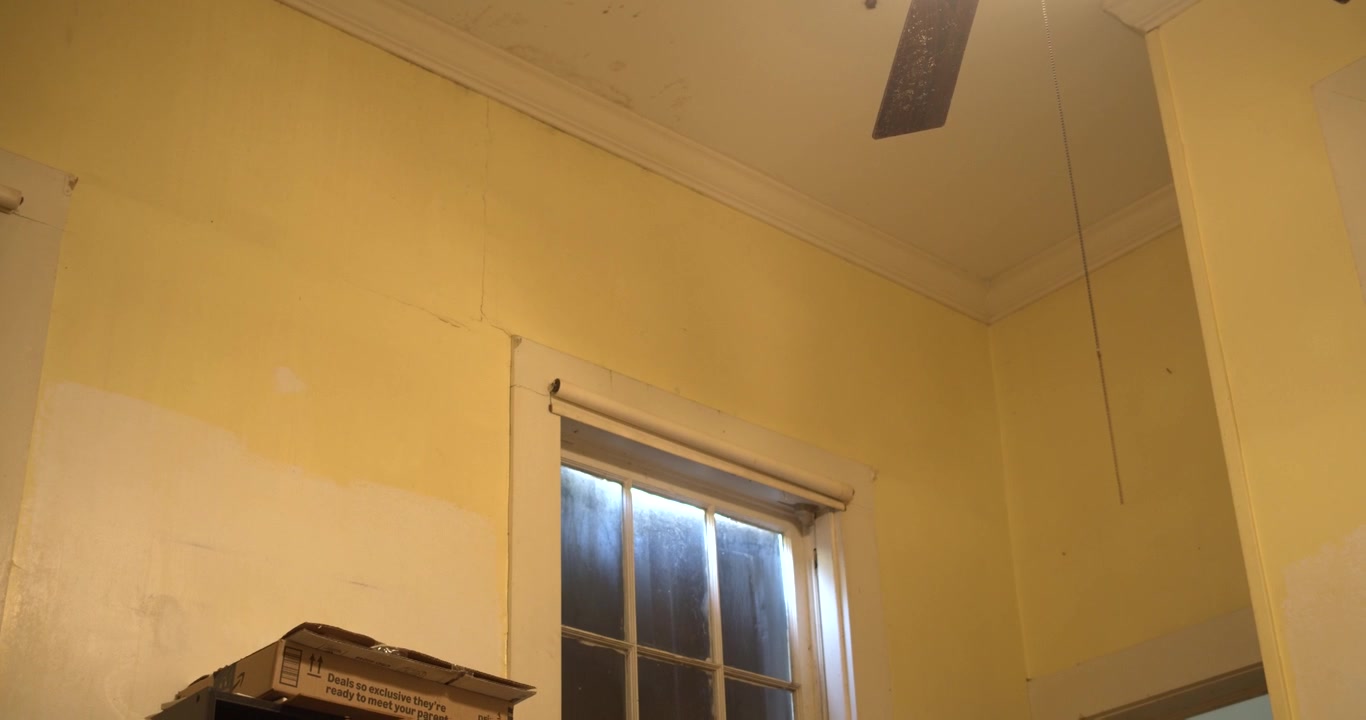 Ripresa a mano libera di una stanza gialla in una casa storica della Louisiana in fase di ristrutturazione a Jeannerette. Interni incompiuti con pareti invecchiate e luce naturale dalla finestra, ideale per concetti di restauro.