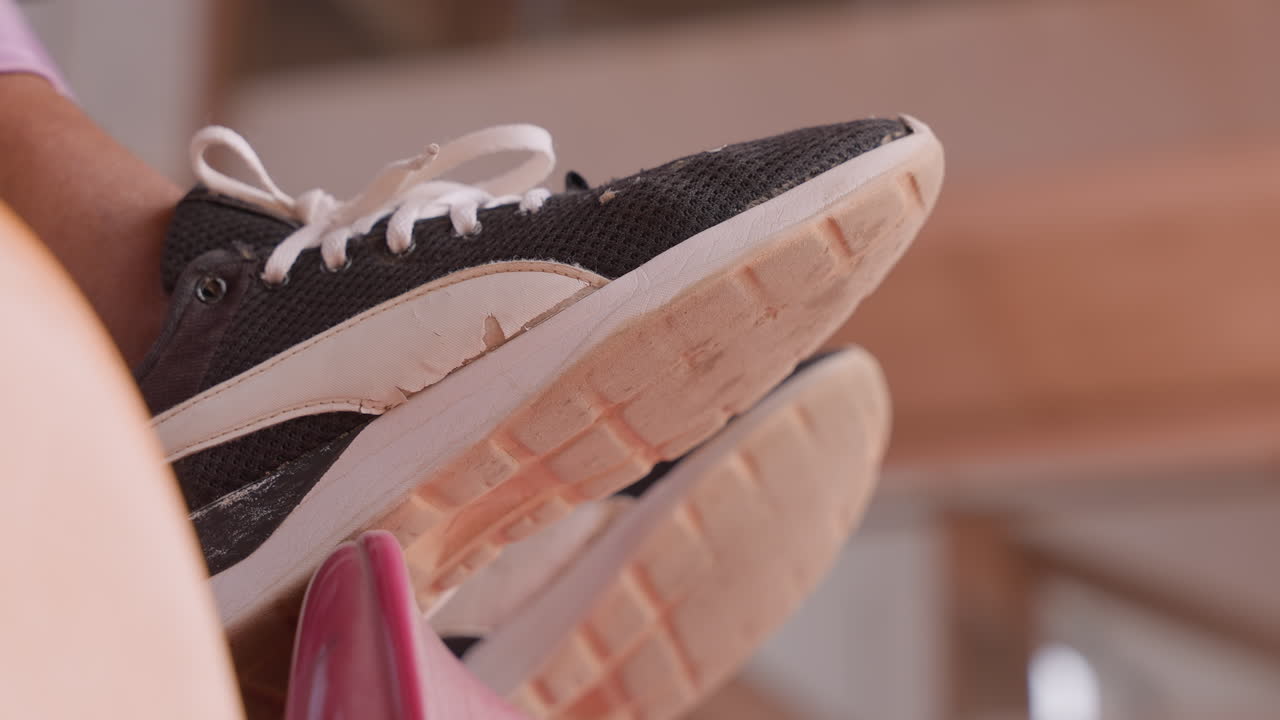 Sneaker sul sedile. Calzatura posizionata su un sedile rosa dello stadio. Primo piano della suola della sneaker su una zona di seduta imbottita. Vista dettagliata della suola della sneaker posizionata su una comoda panca da interni/esterni.