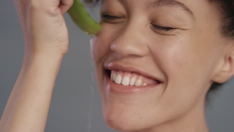 Primer-Plano-Retrato-Hermosa-Mujer-Joven-Sosteniendo-Aloe-Vera-Goteando-Agua-Disfrutando-De-Esencia-Natural-Fresca-Mujer-Juguetona-Sonriendo-Sobre-Fondo-Gris-Concepto-De-Cuidado-De-La-Piel