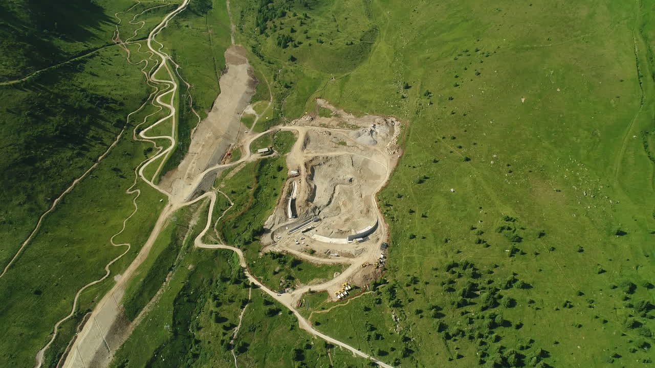 fotografía aérea de un sitio de construcción de una presa en las montañas alpinas